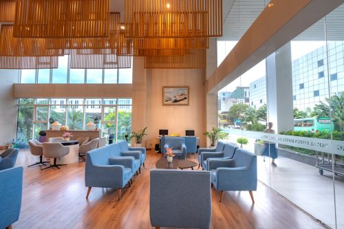 Moderne Hotellobby mit stilvollem Interieur, blauen Sesseln und großen Fenstern, die den Blick nach draußen ermöglichen.